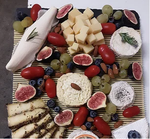Assortiment de fromages, fruits (figues, raisins, myrtilles, tomates cerises) et amandes sur nappe à Pernes-les-Fontaines dans le Vaucluse 84