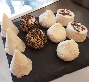 Assortiment de fromages de chèvre artisanaux de différentes formes sur une ardoise sombre à Pernes-les-Fontaines dans le Vaucluse 84